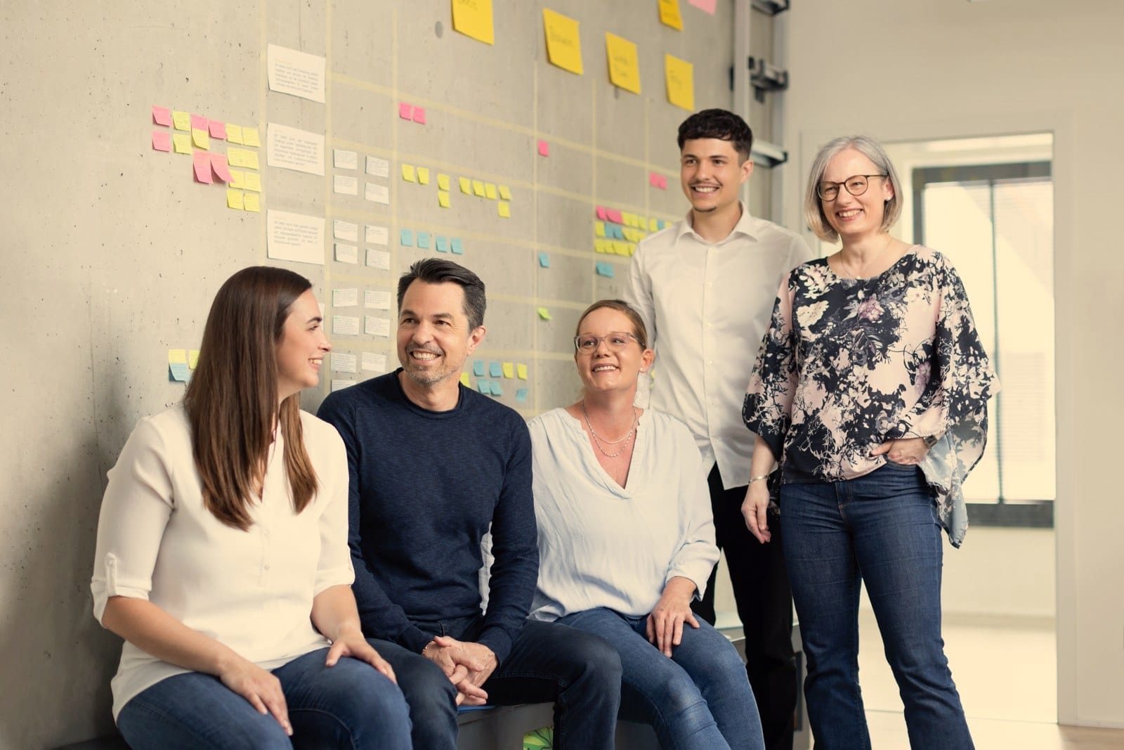 Das Team von REFLECT im Austausch vor einem Kanban-Board